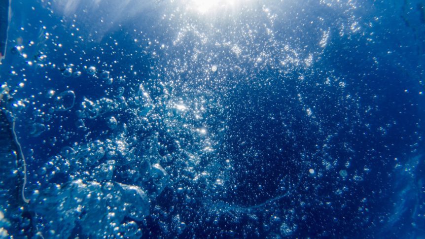 View from underwater with bubbles and the sun